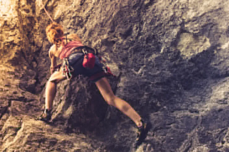 Rock climber ascending a granite cliff with mountain scenery in the Reno Tahoe region.