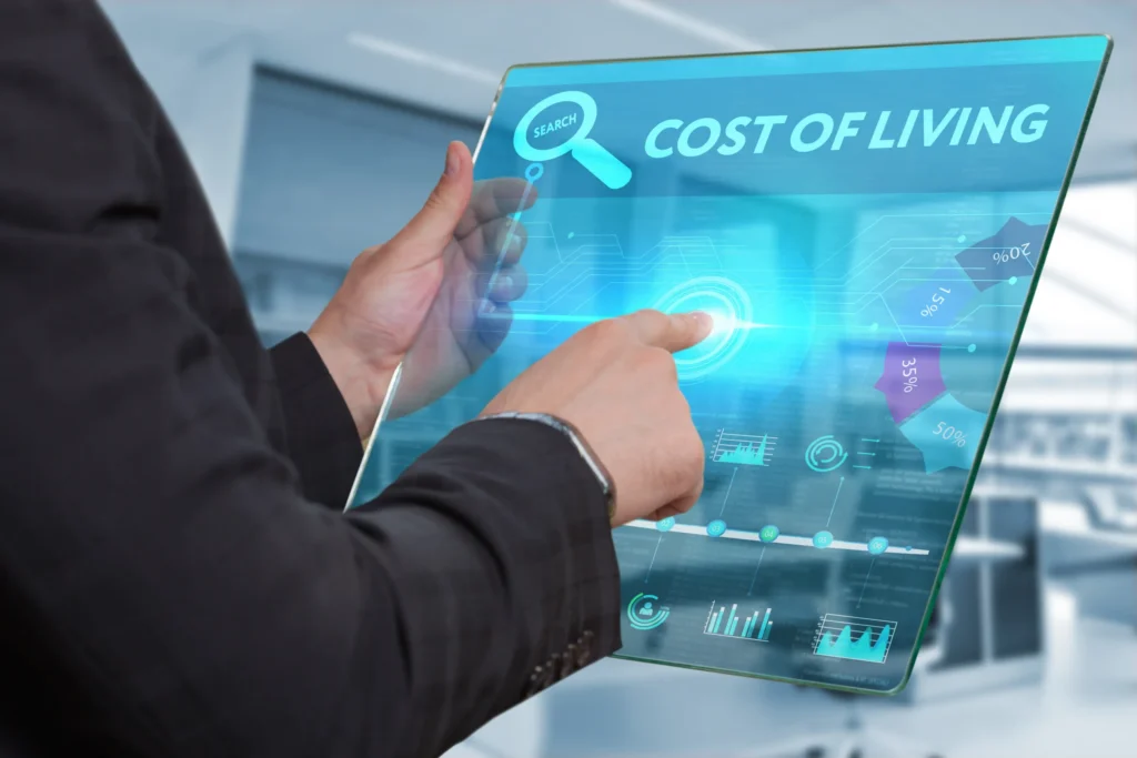 Business professional using a digital tablet displaying cost of living data, financial charts, and housing percentage breakdowns.