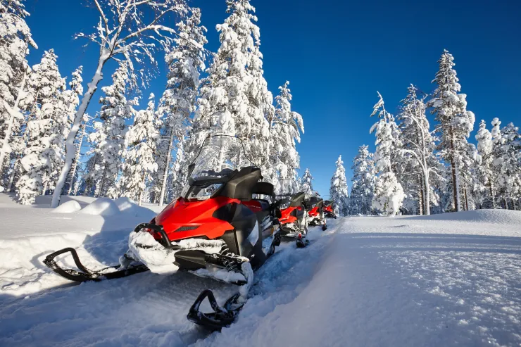 Snowmobiles parked on a snow-covered mountain trail in the Reno Tahoe region with alpine scenery in the background.