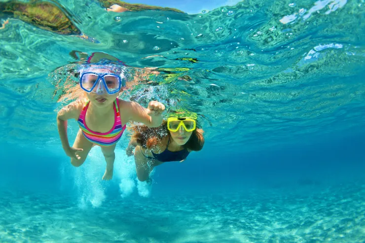 Swimmers enjoying a sandy Lake Tahoe beach with clear water and mountain scenery in the background.